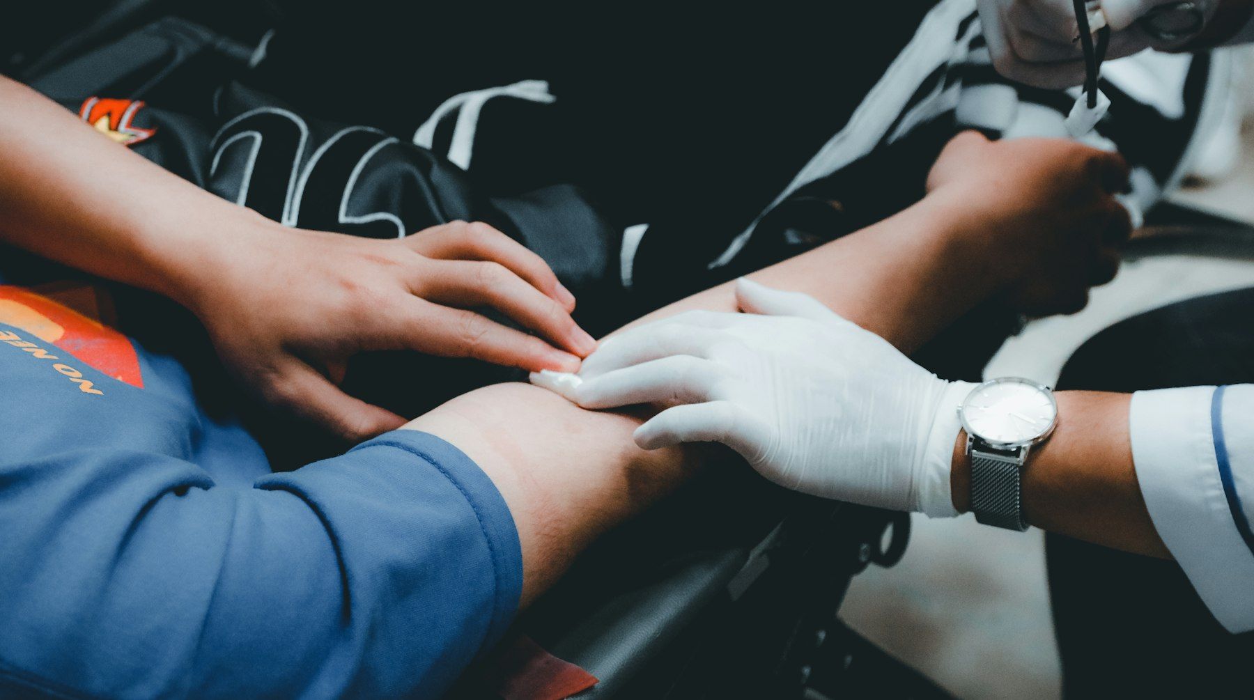 Gloved hands examine a patient’s arm