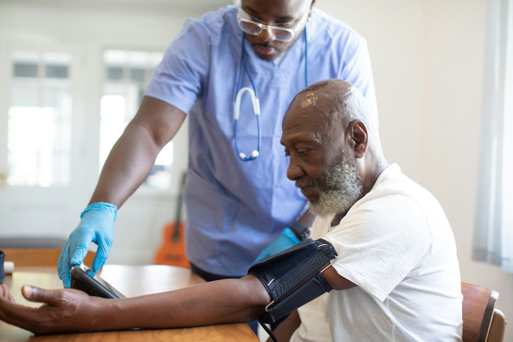 A nurse in gloves takes an older man’s blood pressure
