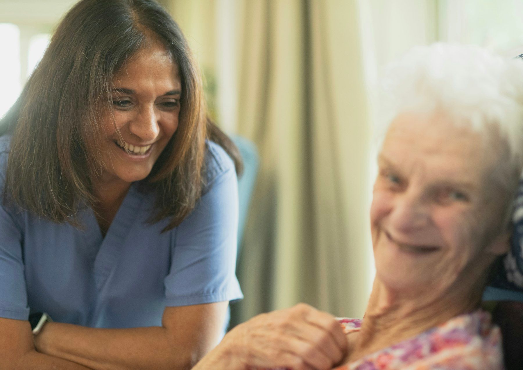 A nurse and an older woman share a laugh