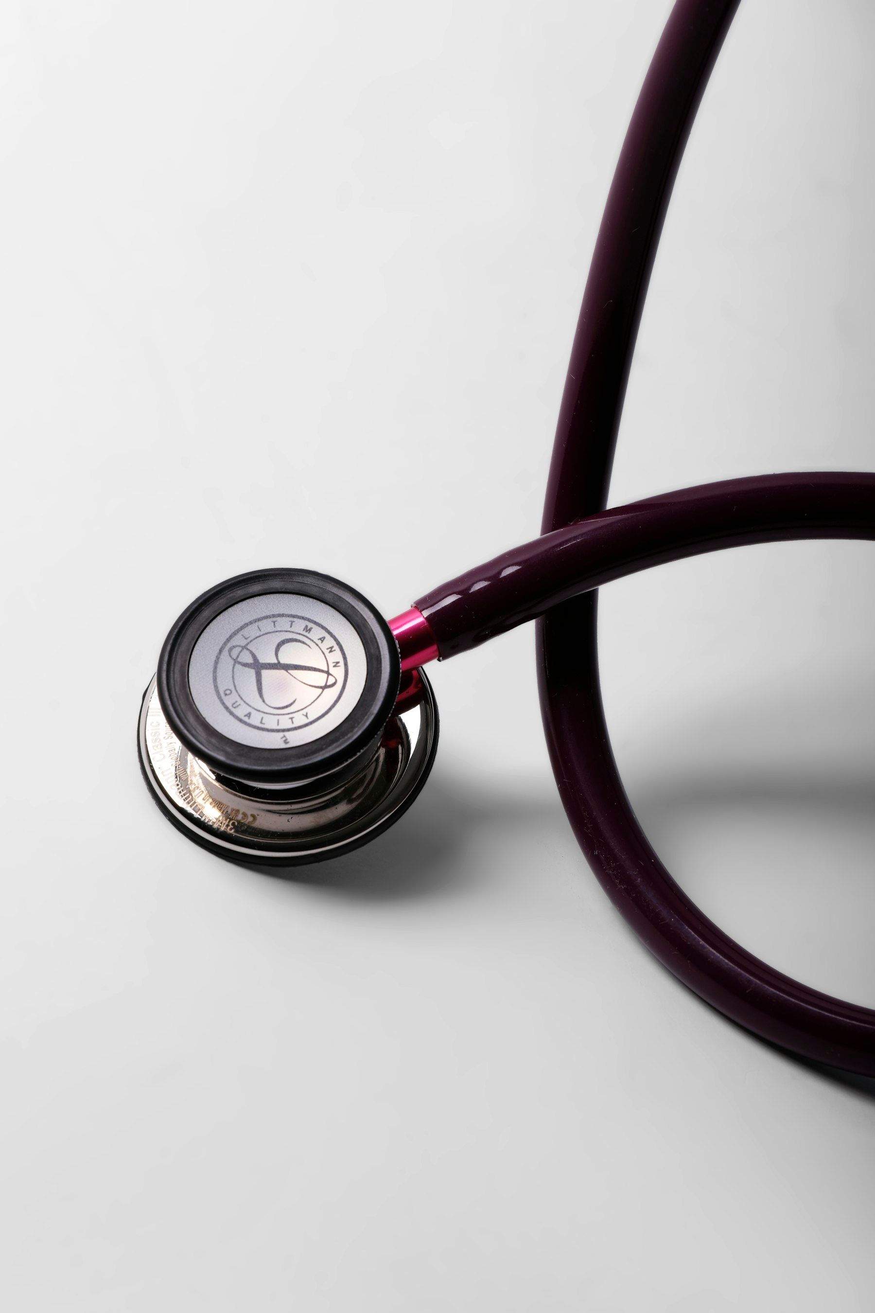 A burgundy stethoscope on a white surface